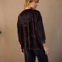 Person wearing a black textured shirt against a beige background