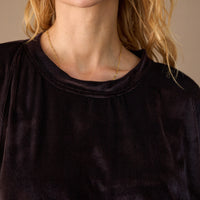 Close-up of a person wearing a black top with a neutral background
