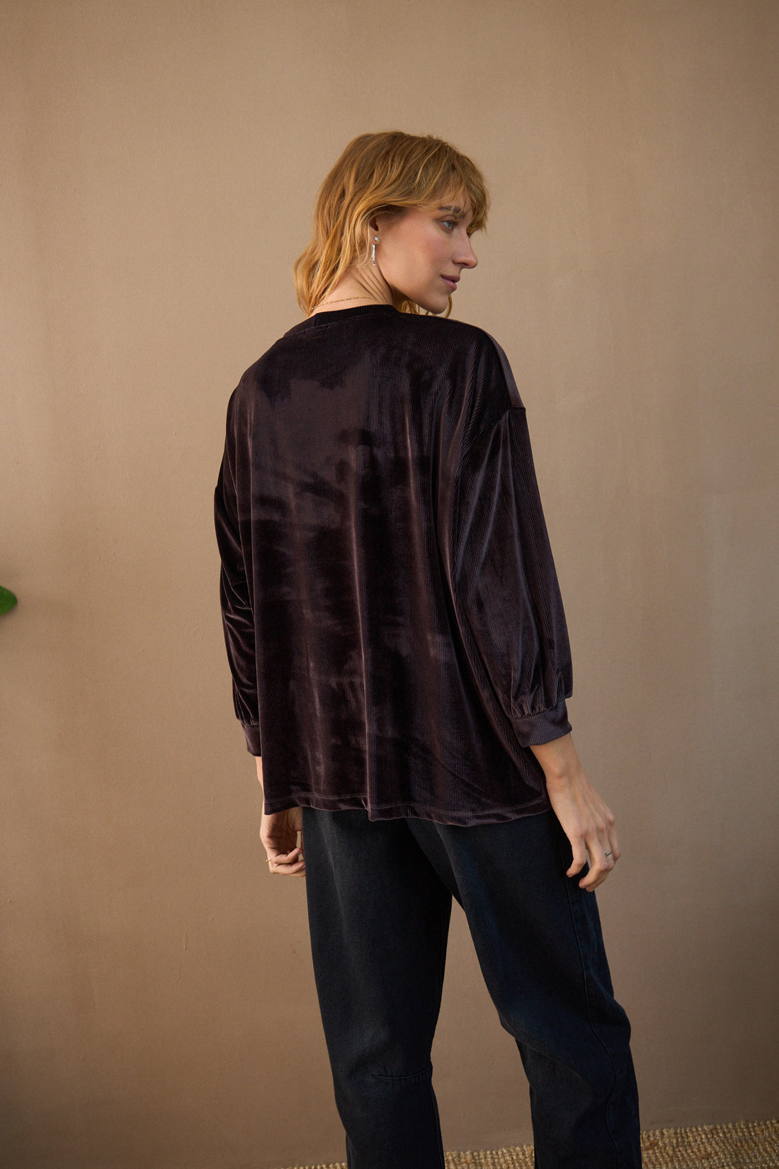 Person wearing a black textured shirt against a beige background
