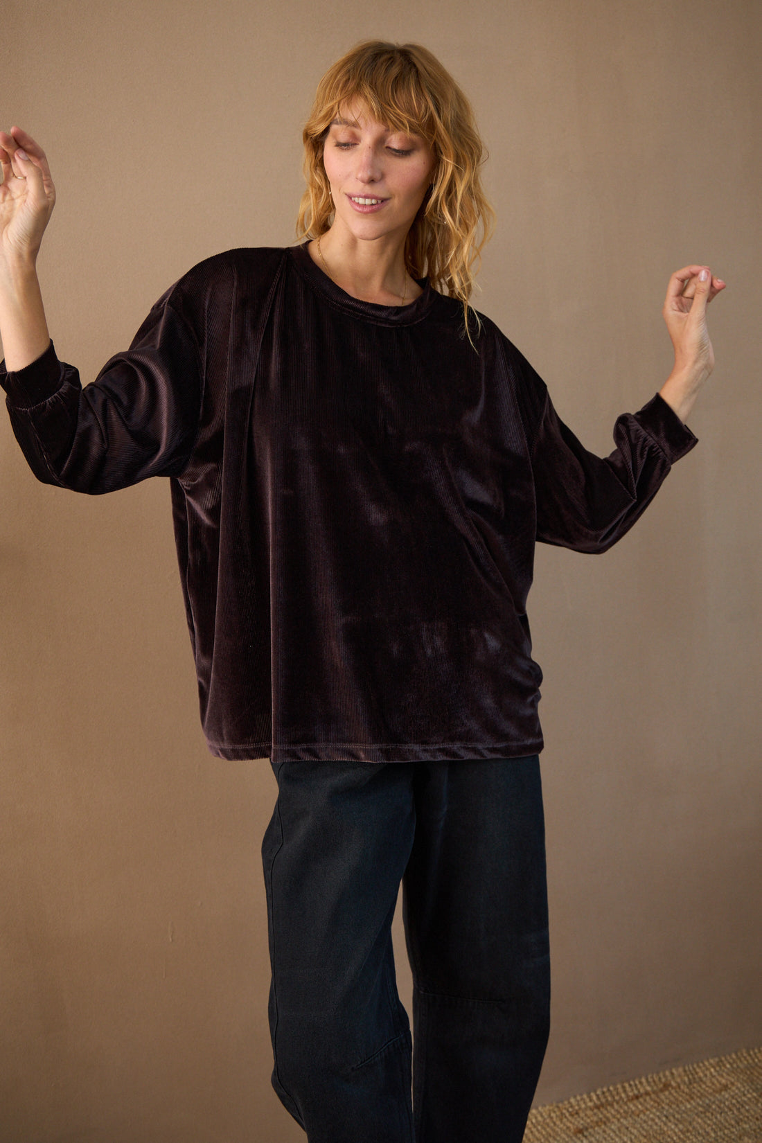 Woman wearing a dark brown velvet outfit against a beige background