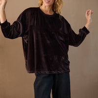 Woman wearing a dark brown velvet outfit against a beige background
